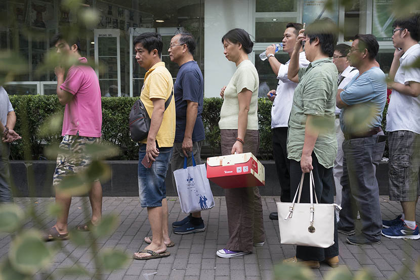People with coupons wait in line to buy mooncakes outside Xin Hua Lou on Fuzhou Road, Shanghai, Sept. 13, 2016. Xiao Muyi/Sixth Tone