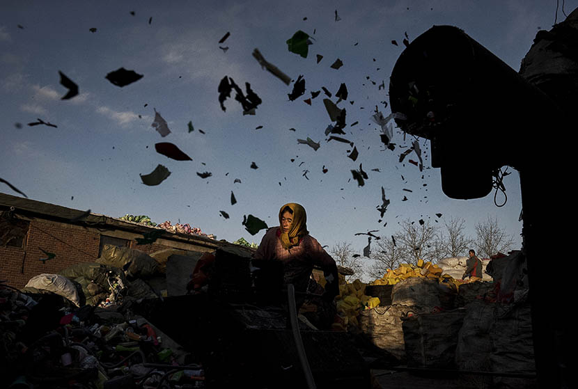 A Chinese laborer in Dong Xiao Kou village, near Beijing, loads a grinding machine with plastics to be recycled, Dec. 15, 2014. Kevin Frayer/Getty Images/VCG