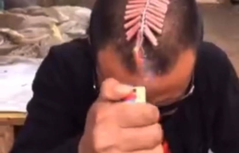 A screenshot from Kuaishou shows a man setting off firecrackers on his head.
