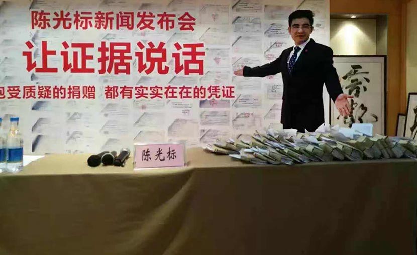 Chen Guangbiao gestures to books on a table during the news conference in Nanjing, Jiangsu province, Sept. 23, 2016. VCG