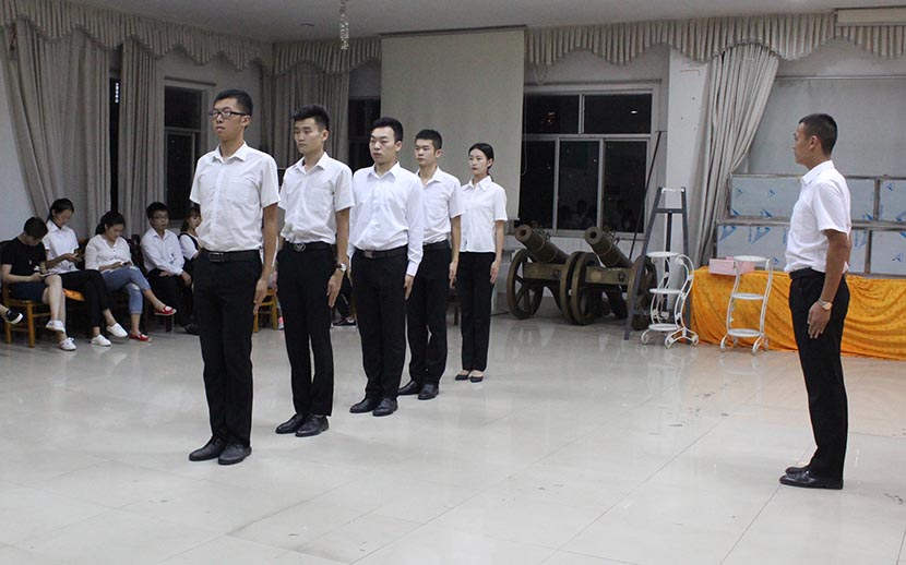 Students practice standing in a way that shows respect at the department of funeral services at Changsha Social Work College, Hunan province, Sept. 20, 2016. Cai Yiwen/Sixth Tone