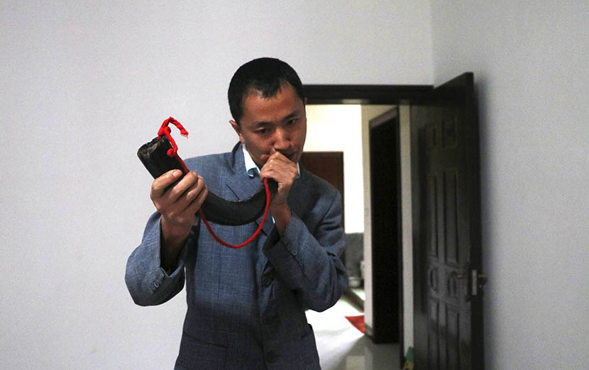 Zhang Gang blows an ox horn at the house where he lives with his father in Shaowo Town, Guizhou province, Sept. 27, 2016. Yin Yijun/Sixth Tone