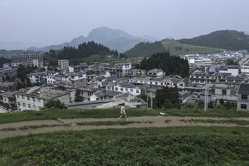A girl runs along the hillside in Shaowo Town, Guizhou province, June 14, 2016. Li Kun/Sixth Tone