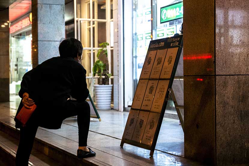 A woman reads an information board with notices of apartments for sale by Lianjia, a large Chinese real estate company, Shanghai, April 18, 2016. In February, home prices in the city jumped 20 percent from the previous year. Zhang Peng/LightRocket via Getty Images/VCG