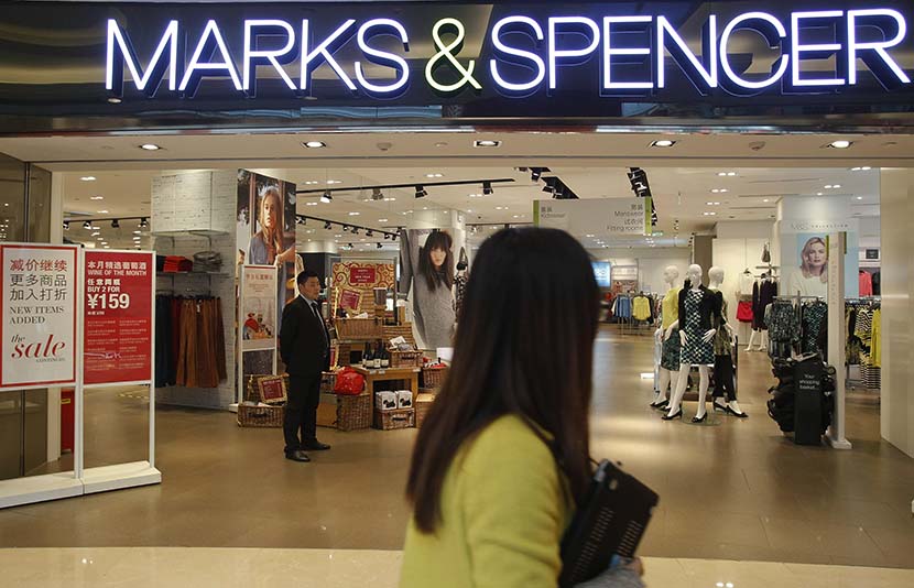 A woman passes by a Marks & Spencer store in Shanghai, March 4, 2015. Gao Zheng/Sixth Tone
