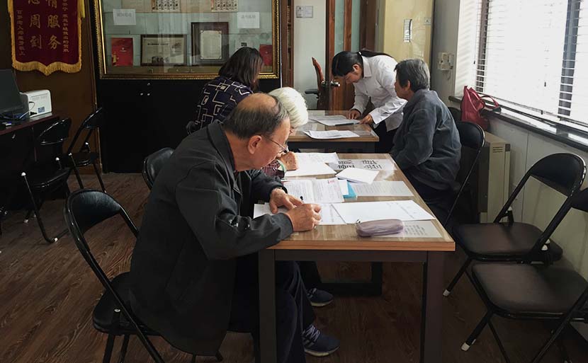 Several elderly people write wills by hand at the China Will Registration Center in Beijing, Oct. 18, 2016. Wang Lianzhang/Sixth Tone