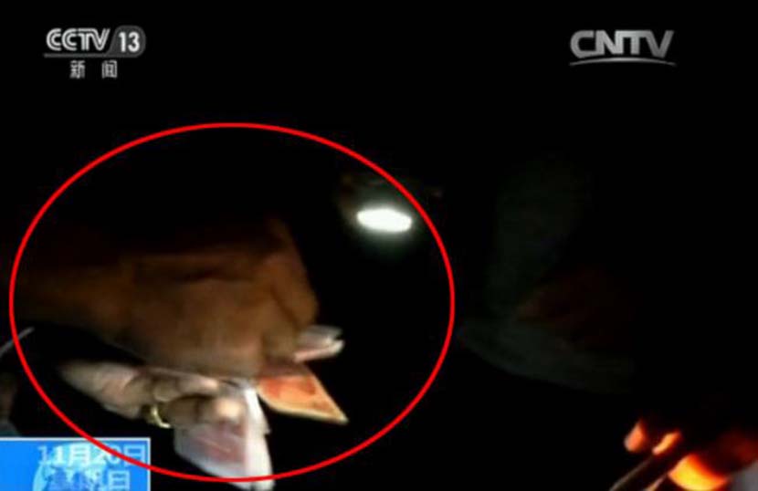 A screenshot from the CCTV report shows a smuggler paying cash to secure safe passage for his truck and its cargo across the China-Vietnam border.