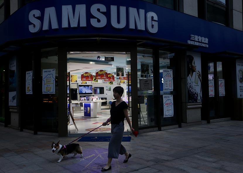 A woman walking a dog passes by a Samsung store in Shanghai, Oct. 11, 2016. Jia Ru/Sixth Tone