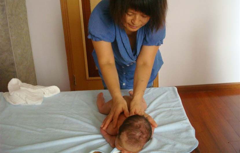 Lian Lanying helps a newborn baby do exercises in Beijing, December 2011. Courtesy of Lian Lanying