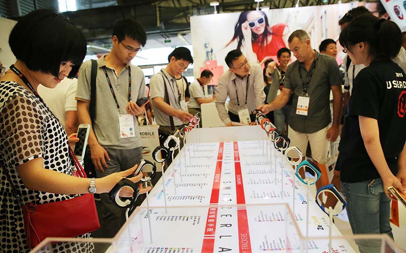 People try out wristwatch-like fitness trackers during a wearable-device exhibition in Shanghai, July 15, 2015. Pei Xin/Xinhua