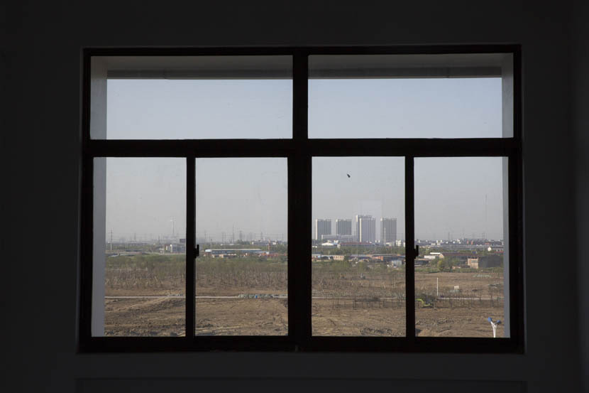 The former site of the Changlong Chemicals Company is seen through the window of a Changzhou Foreign Languages School building, Changzhou, Jiangsu province, April 19, 2016. Zhou Pinglang/Sixth Tone
