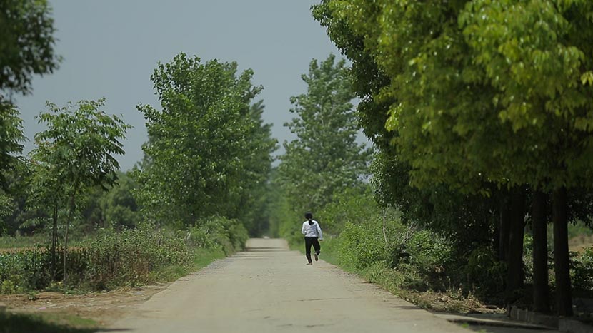 A still frame from ‘Still Tomorrow’ shows Yu Xiuhua walking along a country road. Courtesy of Fan Jian