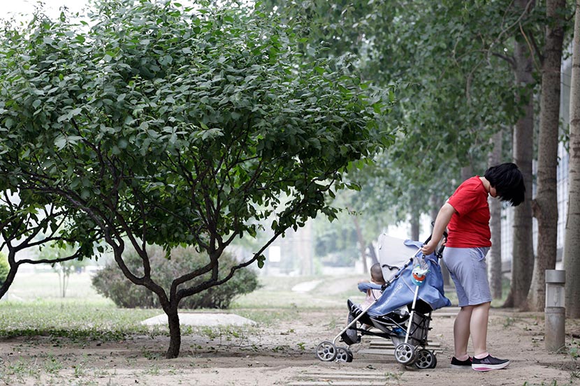 Sisi takes her baby girl through the park in a stroller in Beijing, June 7, 2016. Han Meng/Sixth Tone