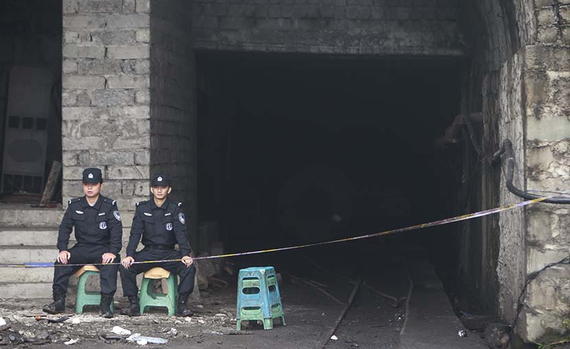 Two security guards sit at the entrance to the Jinshangou coal mine, where a gas explosion killed 33 people in Chongqing, Nov. 2, 2016. Feng/VCG