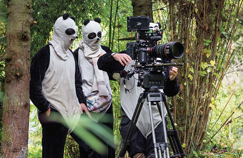 Staff from the crew of ‘Born in China,’ dressed in panda costumes, film a baby panda in Sichuan province.