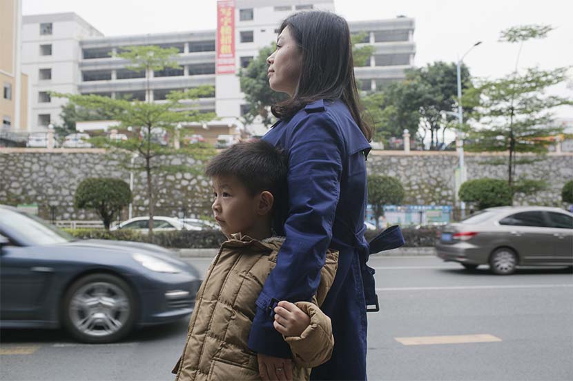 Lan Yanfei waits for a bus with her son in Shenzhen, Guangdong province, Dec. 24, 2016. Zhou Pinglang/Sixth Tone