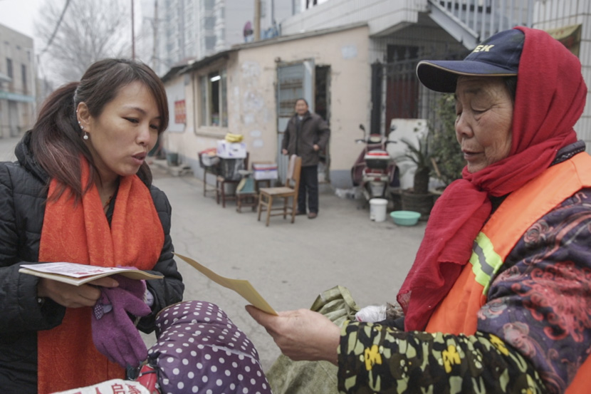 Song Zhenming shows a picture of her missing father to a passerby in Zhengzhou, Henan province, Jan. 1, 2017. Chen Ronghui/Sixth Tone
