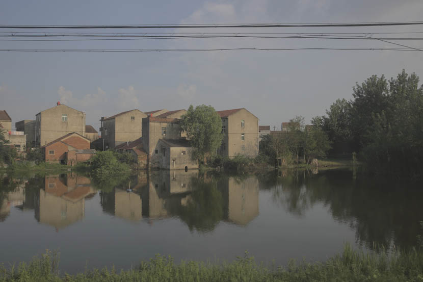 Houses stand along the river in Paizhouwan Township, Hubei province, Aug. 11, 2016. Zhou Pinglang/Sixth Tone