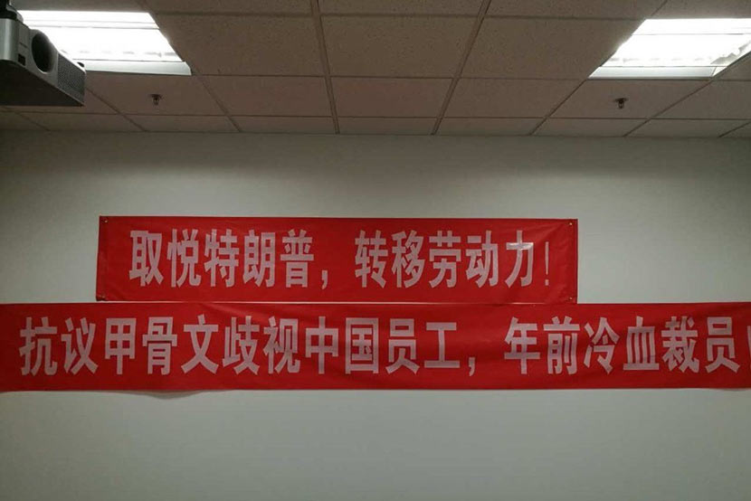An undated photo of a red banner on an office wall reads “Transfer labor for pleasing Trump.” From Weibo