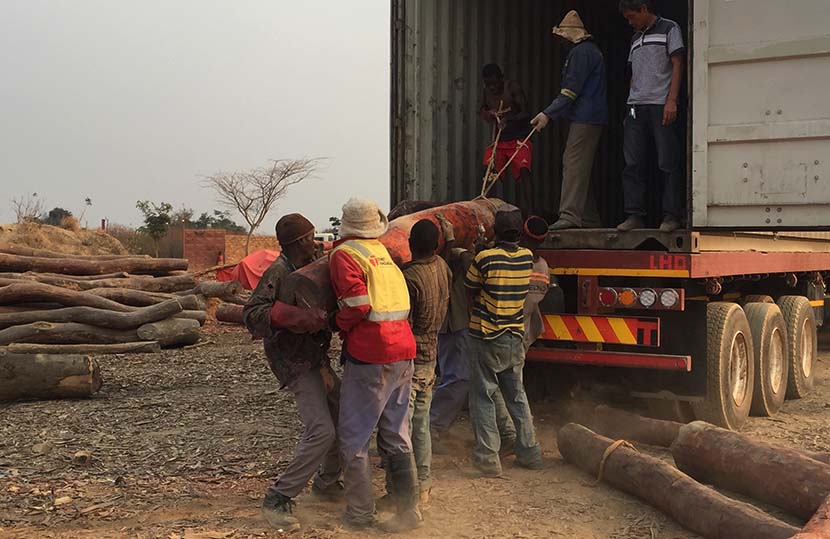 Workers from a bloodwood warehouse operated by Chinese businessmen lift a wood into a truck in Lubumbashi, Congo, Aug. 22, 2016. Shi Yi/Sixth Tone