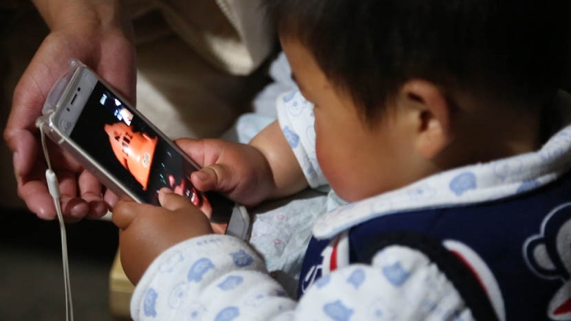 Guo Guo looks at his father Xie Jun during a video call at the family home in Yang Village, Anhui province, April 14, 2016. Liu Lu/Sixth Tone