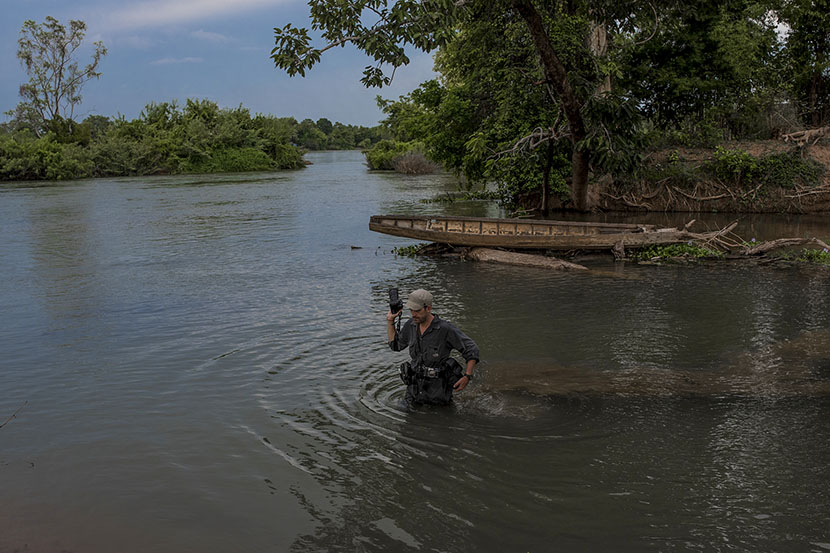 Photographer Luc Forsyth wades through a river. Courtesy of Luc Forsyth