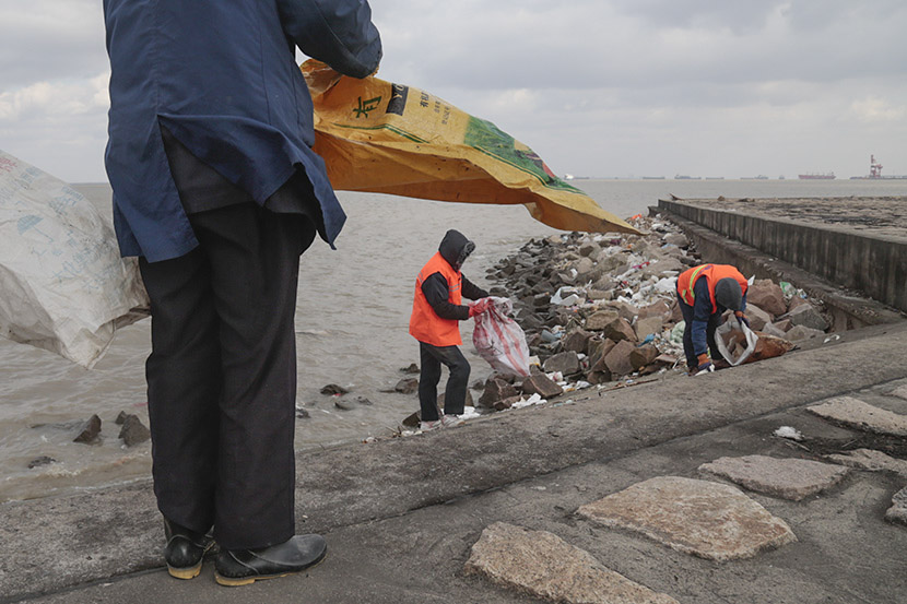 Sanitation workers pick up garbage along the banks of the Yangtze River, Taicang, Jiangsu province, Dec. 27, 2016. Li You/Sixth Tone