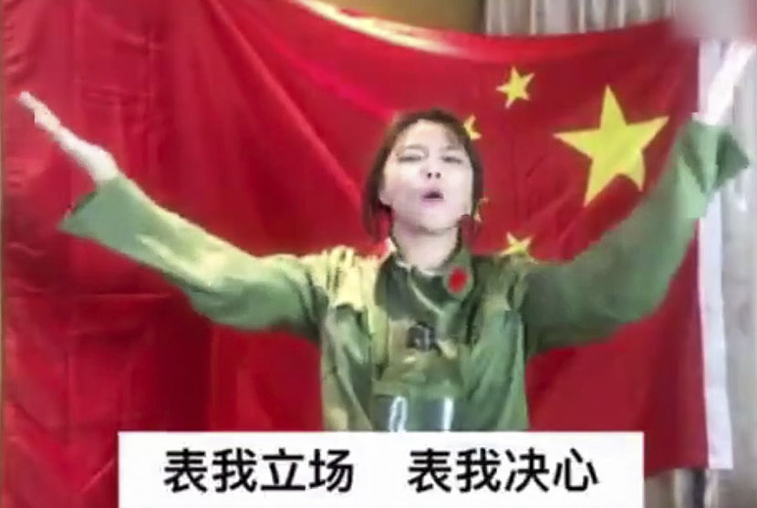 Mu Yalan stands in front of a Chinese flag and raises her hands in a screenshot from an anti-Lotte video posted on March 13, 2017.