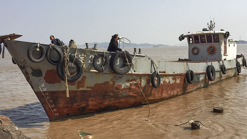A boatman and his wife moor their cargo ship at Qili Peak as the tide rises in Zhejiang province, Feb. 28, 2017. Fu Danni/Sixth Tone
