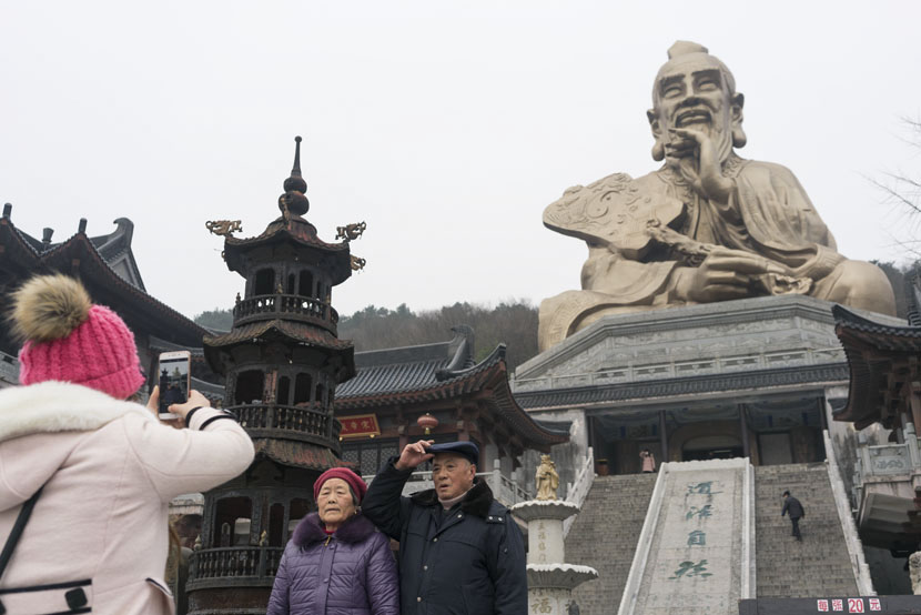 Tourists take photos at the entrance of Yuanfu Wanning Temple, Jurong City, Jiangsu province, Jan. 10, 2017. The complex includes a massive statue of Lao-tzu, the founder of Taoism. Thomas Cristofoletti for Sixth Tone