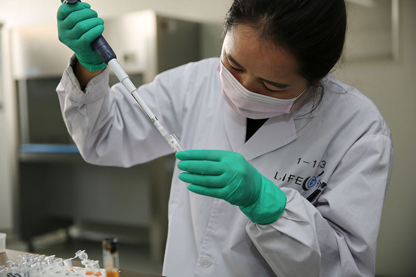 A laboratory technician transfers a sample for a genetic test in Xi’an, Shaanxi province, Dec. 1, 2016. Wei Yongxian/VCG