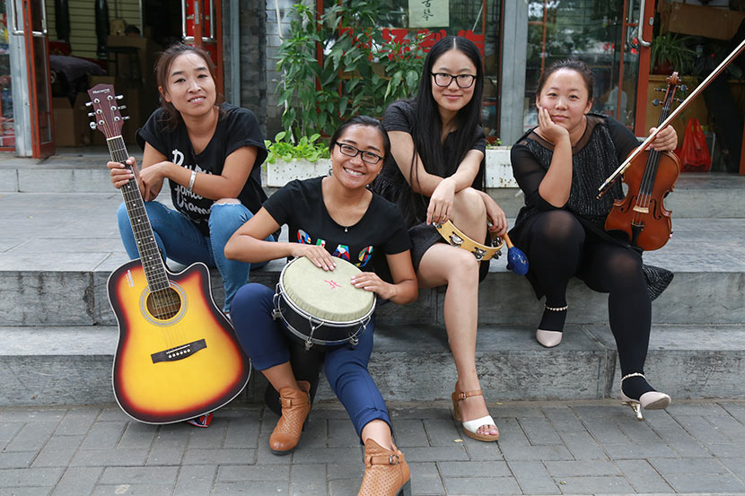 Duan Yu, Ren Juan, Xiong Ying, and Ma Wei pose for a photo in front of the violin shop where they rehearse in Beijing, Sept. 17, 2016. Courtesy of Jiu Ye