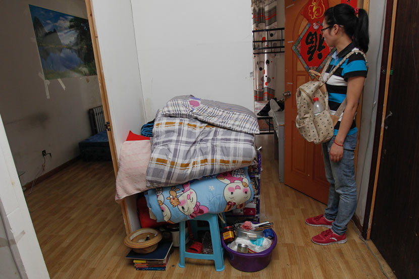 A tenant stands with her belongings after her ‘secondary landlord’ forced her to leave her apartment in Beijing, June 27, 2013. VCG