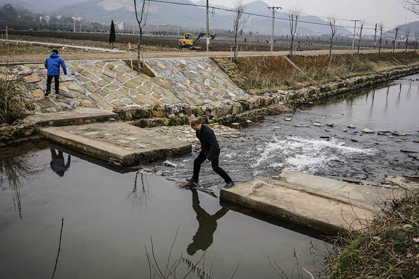 Ye steps across a stream while conducting a field investigation for his company in Zhuji, Dec. 23, 2015. Chen Ronghui/Sixth Tone