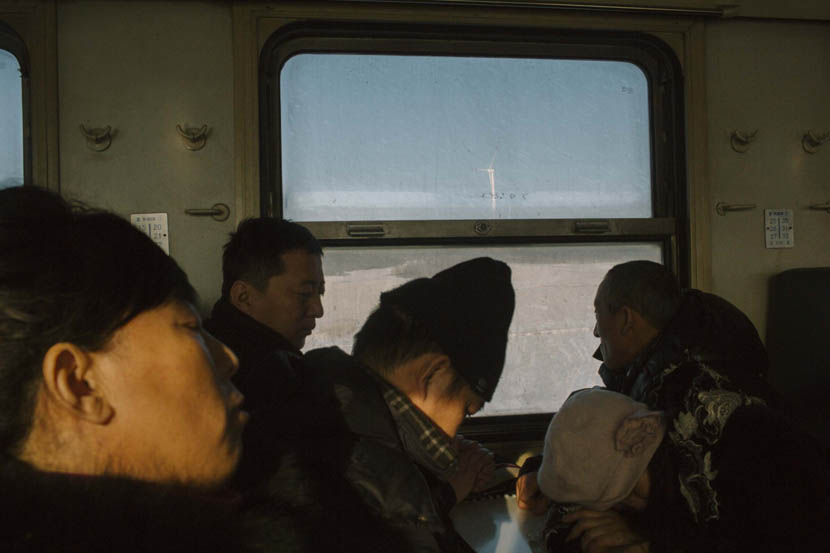 A commuter train carrying miners travels past wind turbines in Shuangyashan, Heilongjiang province, Jan. 11,2016. Zhou Pinglang/VCG
