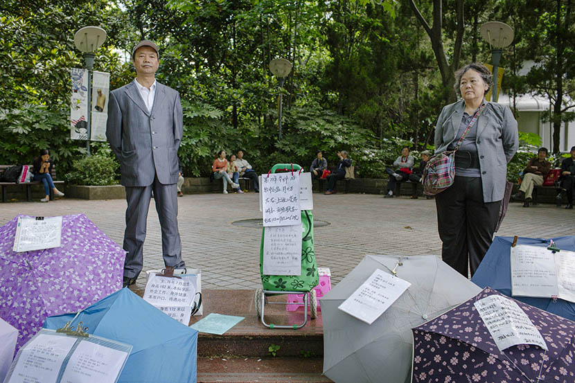  Parents stand behind umbrellas listing information on potential matches at the matchmaking corner in People's Park in Shanghai, May 17, 2015. Zhou Pinglang/Sixth Tone