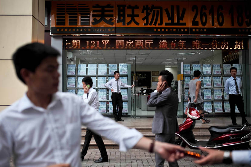 Agents stand in front of a real estate agency, in Shenzhen, Aug. 18, 2013. Zhou Pinglang/Sixth Tone