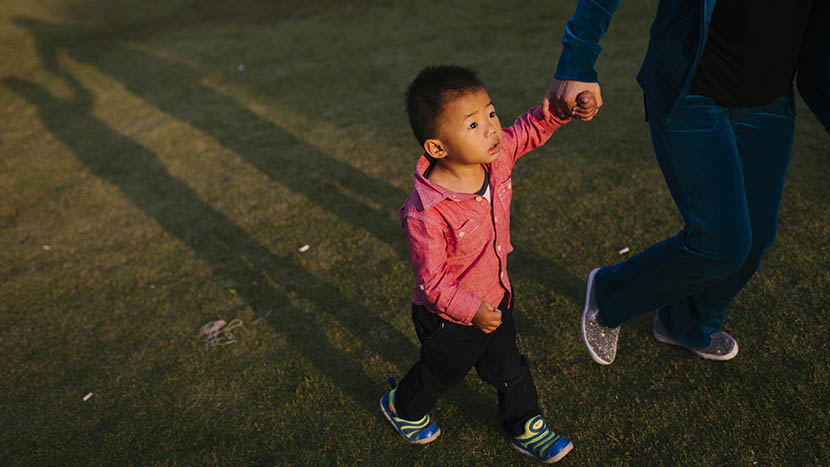 Tongtong is led by his nanny in a playground near his home, in Shanghai, Oct. 12, 2015. Zhou Pinglang/Sixth Tone