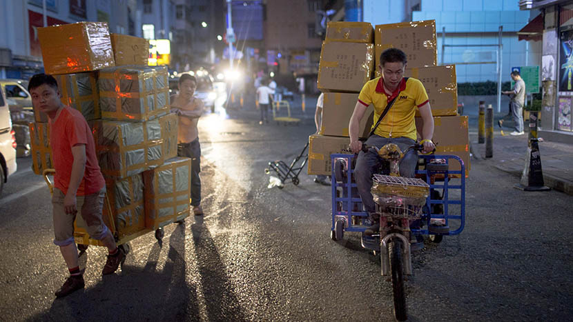 A courier carries packages on his electric freight tricycle at night, Shenzhen, Guangdong province, April 8, 2016. Zhou Pinglang/Sixth Tone