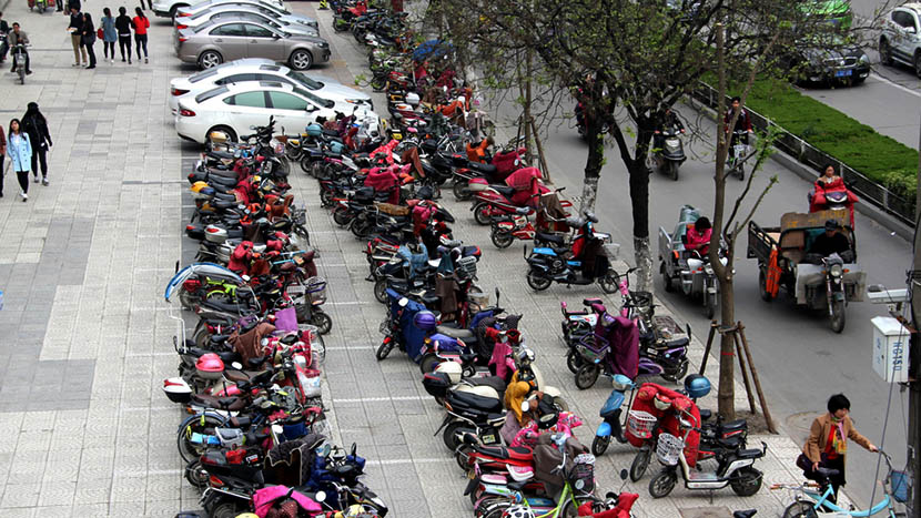 E-bikes, motorcycles, and cars parked on side of the road in Suzhou, Anhui province, April 11, 2016. IC