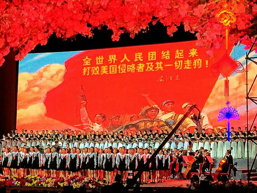 Performers in front of a backdrop featuring the slogan: ‘The whole world must unite to defeat American invaders and their running dogs’ at the ‘In Fields of Hope’ concert at the Great Hall of the People in Beijing, May 2, 2016. @PuBaoyi from Weibo