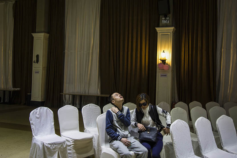 Sun Wenlin, seated with his mother, massages his neck after the wedding ceremony rehearsal in Changsha, Hunan province, May 16, 2016. Wu Yue/Sixth Tone