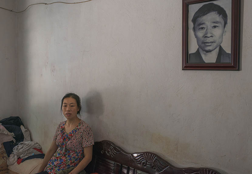 Gu Xia sits by a portrait of her deceased father in Jinghong, Yunnan province, April 17, 2016. Wu Yue/Sixth Tone