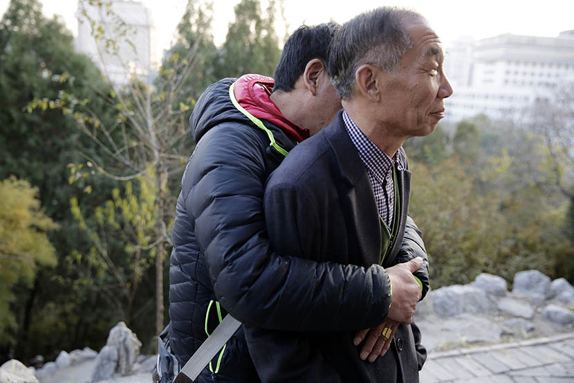Peng Huijie is hugged by man at Dongdan Park in Beijing, Nov. 24, 2014. Dong Dalu/Sixth Tone
