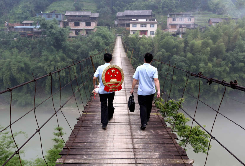 Two judges cross a bridge on their way to a village courthouse in Rongshui, Guangxi Zhuang Autonomous Region, May 21, 2015. Long Tao/VCG