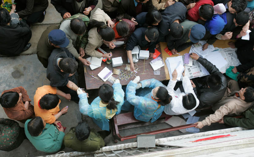 Villagers wanting to take HIV tests crowd around a table in Wenlou Village, Shangcai County, Henan province, April 2006. Xu Haifeng/Sixth Tone