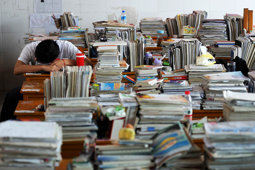 A senior high school student surrounded by piles of books sleeps on the desk in Maotanchang High School in Liuan, Anhui province, June 5, 2013. Wu Fang/VCG