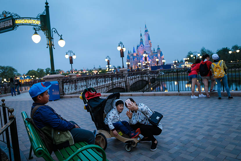 A woman takes a selfie with her son at Shanghai Disneyland during its soft opening, May 13, 2016. Liu Xingzhe/Sixth Tone