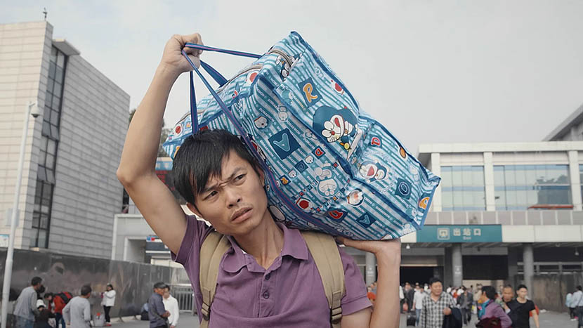 A still from ‘The Verse of Us’ shows poet worker Wu Niaoniao carrying luggage through Guangzhou as he looks for work. Courtesy of MeDoc.