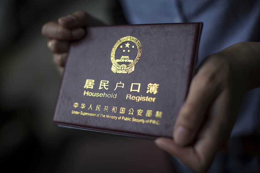 A woman holds her household registration document, or ‘hukou,’ in Shanghai, May 5, 2015. Yang Shenlai/Sixth Tone